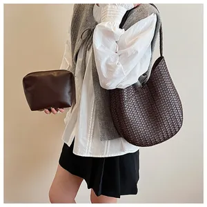 Detail der dunkelbraunen gewebten Hobo-Tasche und glatten Leder-Clutch im Set mit Model