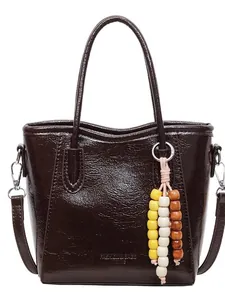 Minimalistische dunkelbraune glänzende Eimertasche mit Tragegriffen und Perlenanhänger