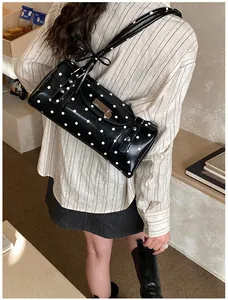 Sac Boston à pois avec nœuds porté à l'épaule dans un décor intérieur chaleureux