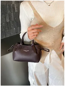 Detail of dark brown leather tote with golden logo text and drawstring side accents