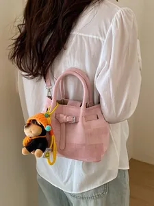 Pink minimalist crossbody bag with cute dog pendant shown on shoulder for daily fashion style