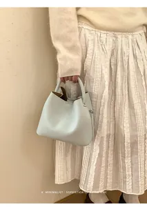 Close-up of minimalist light blue bucket bag showing lychee grain leather and brown interior