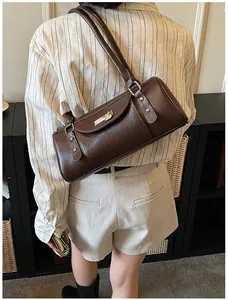 Détail d'un sac Boston marron avec fermoir en métal argenté et texture fine en cuir PU