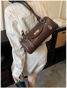 Détail du sac cylindre marron foncé avec boucle dorée et rivets argentés sur la bandoulière