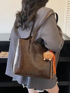 Vintage large brown leather tote bag with monster charm shown on model's shoulder