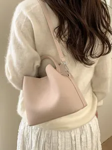 Minimalist light pink leather bucket bag worn by model with textured shoulder strap