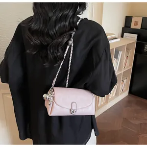 Détail du sac bandoulière rose clair avec chaîne argentée et breloque lapin sur cuir
