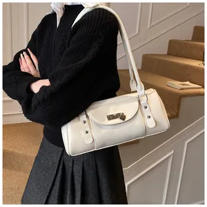 Sac baguette blanc avec pendentif cœur en métal et rivets porté par un mannequin