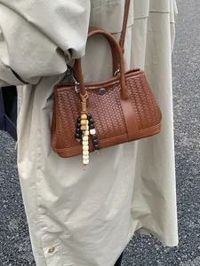 Bruine geweven crossbodytas met etnische kralen bij een beige trenchcoat outfit