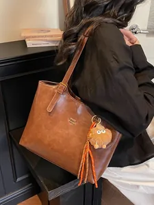 Vintage large brown leather tote bag with pompom charm worn by model in retro interior