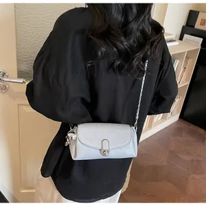 Détail d'un petit sac baguette avec chaîne, serrure en métal et breloque sur un modèle