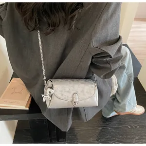Détail du sac baguette argenté métallisé avec chaîne et petit pendentif lapin