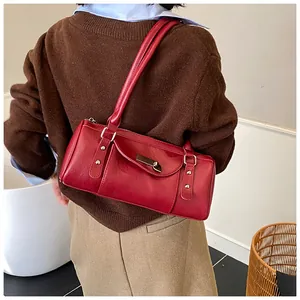 Sac Boston rétro rouge porté à l'épaule en cuir brillant avec des rivets argentés