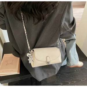 Vue détaillée du sac baguette en cuir crème avec chaîne argentée et bijou de sac