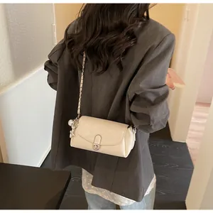 Sac baguette beige chic avec charm ours et bandoulière chaîne sur un mannequin femme