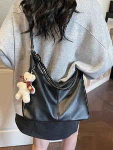 Black leather hobo tote bag with a knotted strap and a cute white teddy bear charm