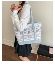 Detail of light blue tote bag featuring cute cartoon foal prints and brand leather logo