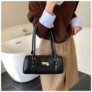 Détail du sac polochon noir avec pendentif cœur en métal et bandoulière en cuir souple