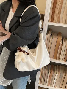 White soft leather hobo tote bag with knotted strap and plush bear charm on a model