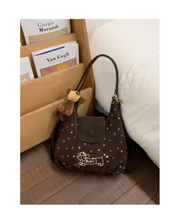 Detail of dark brown suede tote bag with star patterns and a cute puppy plush charm