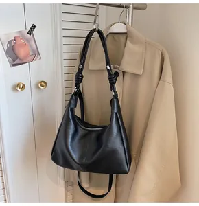Detail of black hobo tote bag featuring knotted metal hardware and smooth leather texture