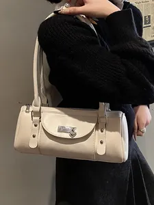 Sac baguette crème chic avec pendentif cœur argenté porté sur un pull noir élégant
