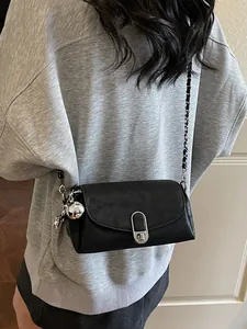 Sac baguette chic en cuir noir avec fermoir rotatif argenté et bandoulière en chaîne