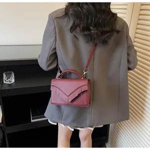 Chic burgundy envelope handbag with fringe detail shown on a model in a modern setting