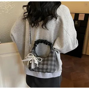 Detail of grey checkerboard bag with pleated handle, cartoon bear, and pearl charm
