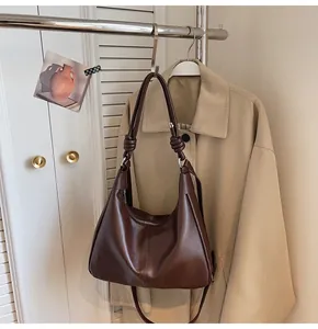 Detail of dark brown tote with glossy leather texture and stylish knot on the shoulder strap