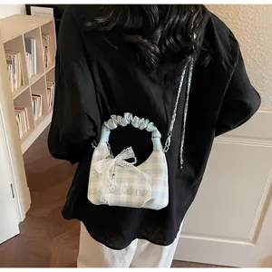 Detailed view of checkered bag with embroidered bears and pearl pendant on a model