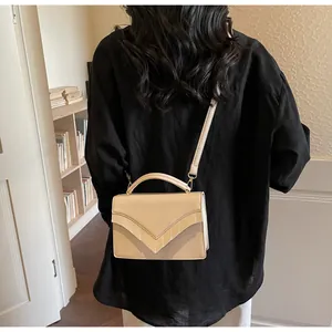 Detail of beige shoulder bag featuring V-shaped layered flap and textured leather