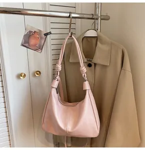 Detail of light pink hobo shoulder bag with knot strap hanging on a metal rack