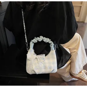 Detail of blue plaid purse with cloud handle, lace bow, and pearl charm accents