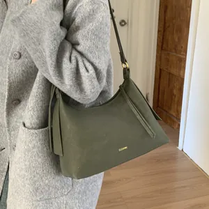 Minimalist deep green leather dumpling bag with fringe worn with a stylish gray wool coat