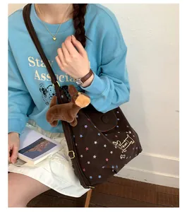 Detail view of the brown canvas tote bag with puppy prints and a soft plush toy pendant