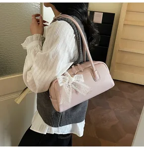Détail d'un sac à bandoulière en cuir grainé rose clair orné d'un nœud en dentelle blanche