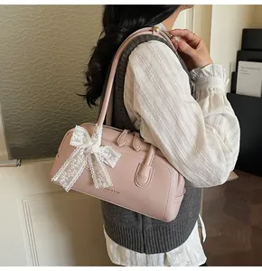 Détail du sac Boston rose avec nœud en dentelle blanche et logo gaufré