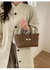 Close-up of the brown lychee-pattern leather texture and golden metal lock detail
