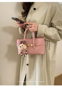Detail of pink lychee leather baguette bag with gold buckle and teddy bear charm