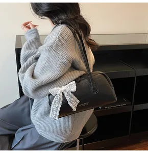 Sac Boston en cuir litchi noir avec un grand nœud en dentelle blanche à l'épaule
