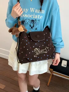 Dark brown star print messenger bag with puppy embroidery and plush charm on model
