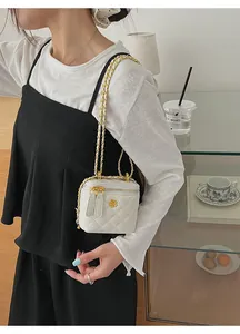 Detail of mini quilted ivory crossbody bag featuring a golden camellia flower metal clasp