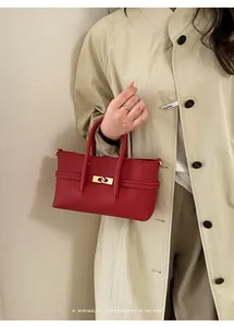 Detail of red lychee grain leather handbag with gold metal ring buckle on beige coat