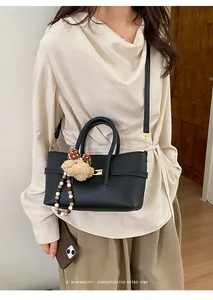 Detail of black lychee grain leather bag with a mushroom plush charm and gold hardware