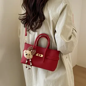 Red pebbled leather baguette bag with golden lock and plush bear charm on model
