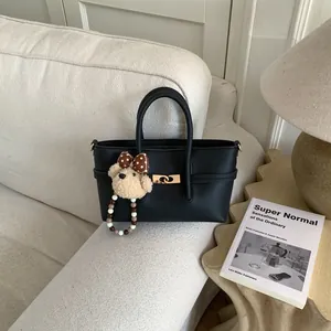 Black litchi grain leather baguette bag with gold hardware and plush bear charm