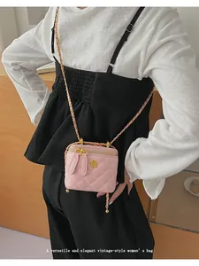 Close-up of pink quilted vanity bag with golden flower buckle and chain strap
