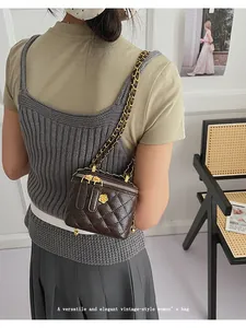 Detail of coffee quilted mini bag with gold camellia logo and metal chain strap