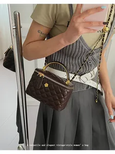 Detail of dark brown quilted vanity case with golden camellia and chain strap